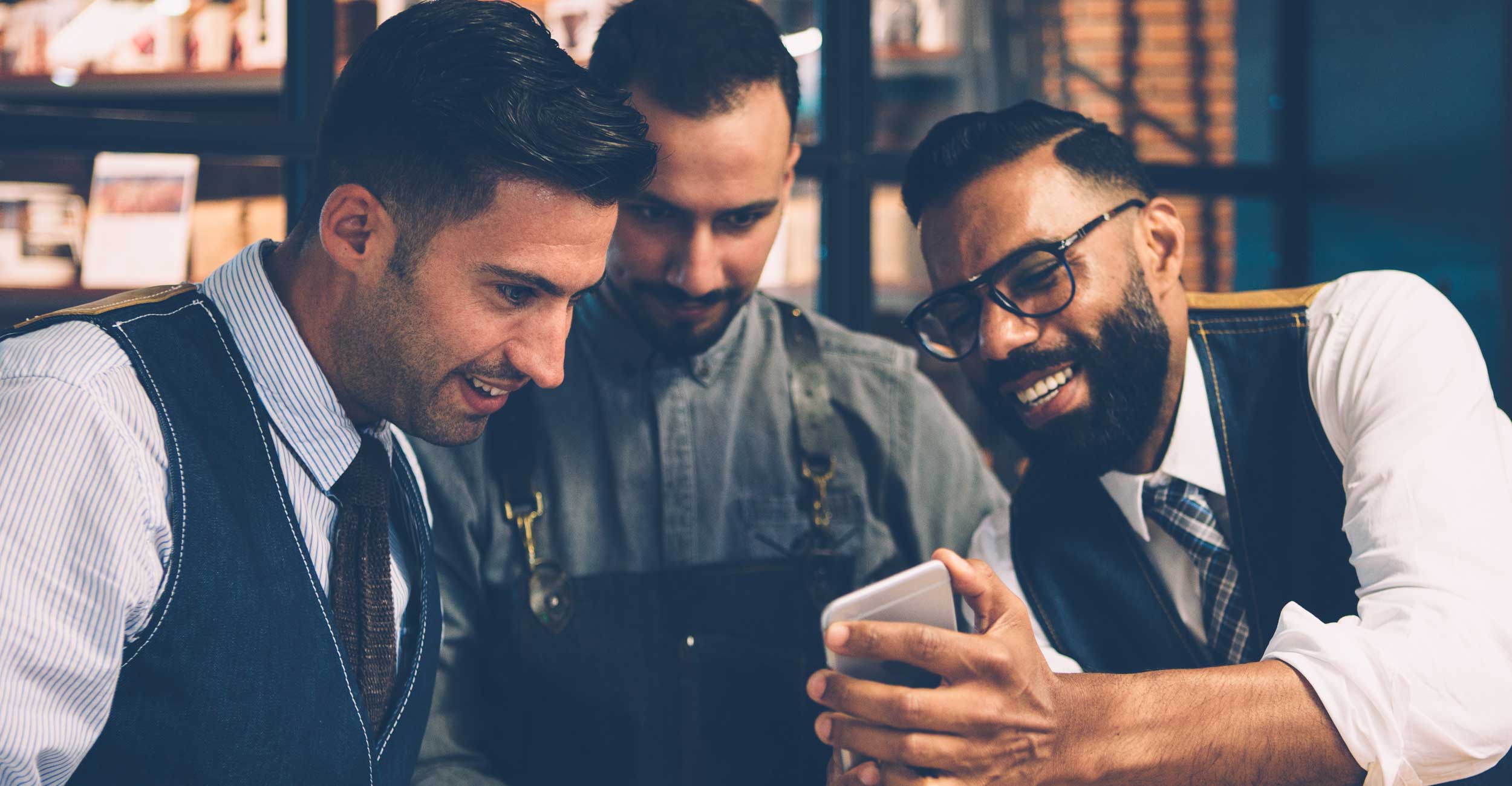 Three friends laughing together over a phone